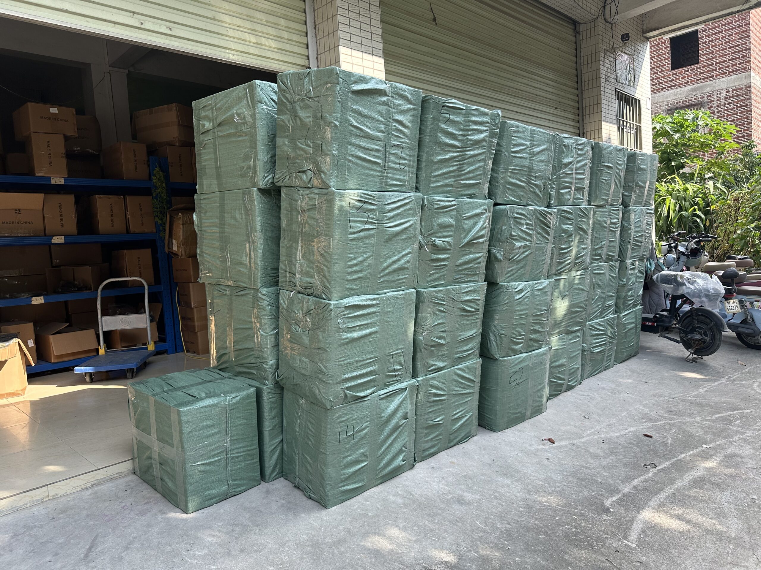 Cartons wrapped in green stretch film, stacked at the factory entrance