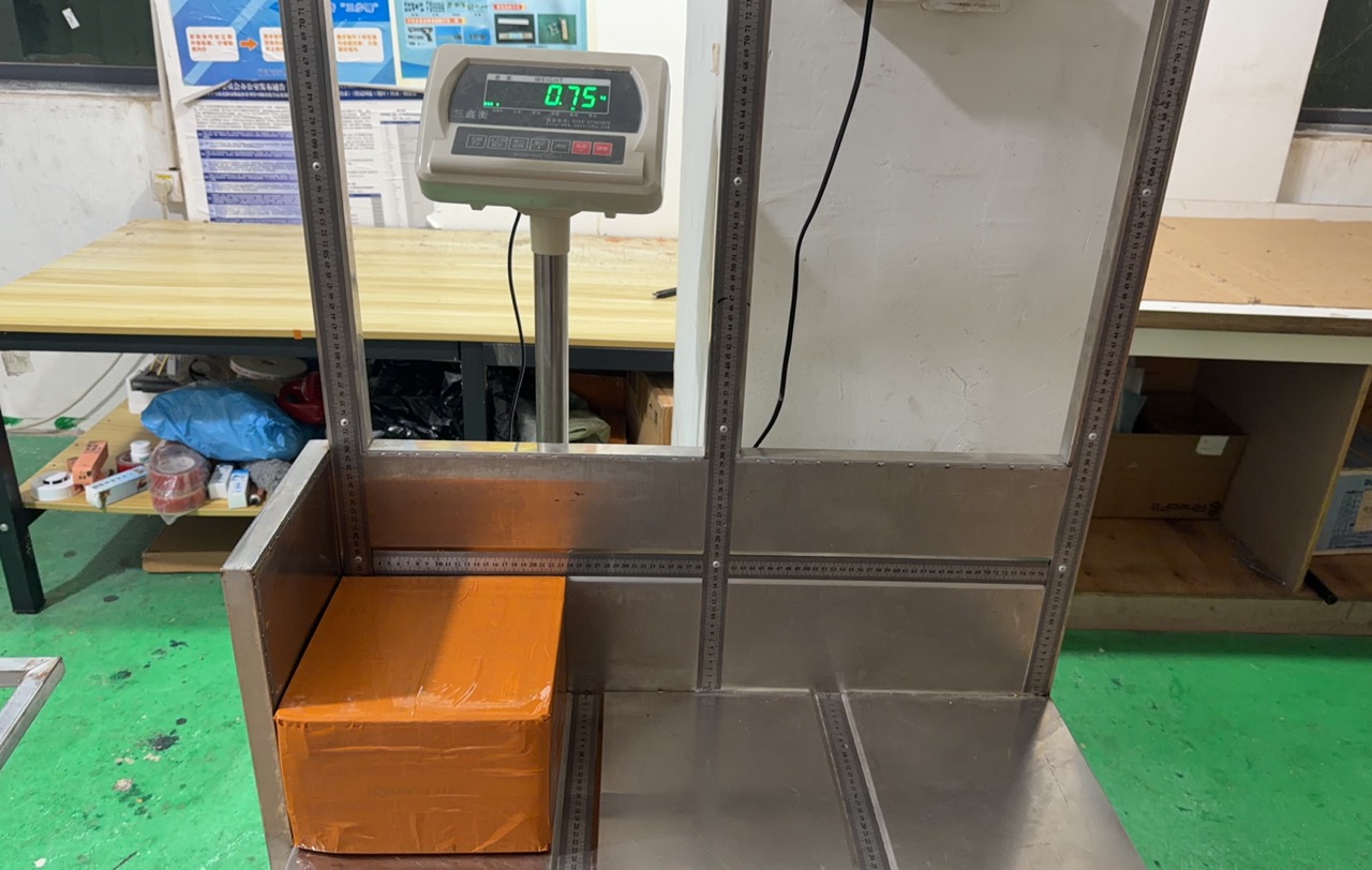 Orange carton on a platform scale with the weight shown on the display