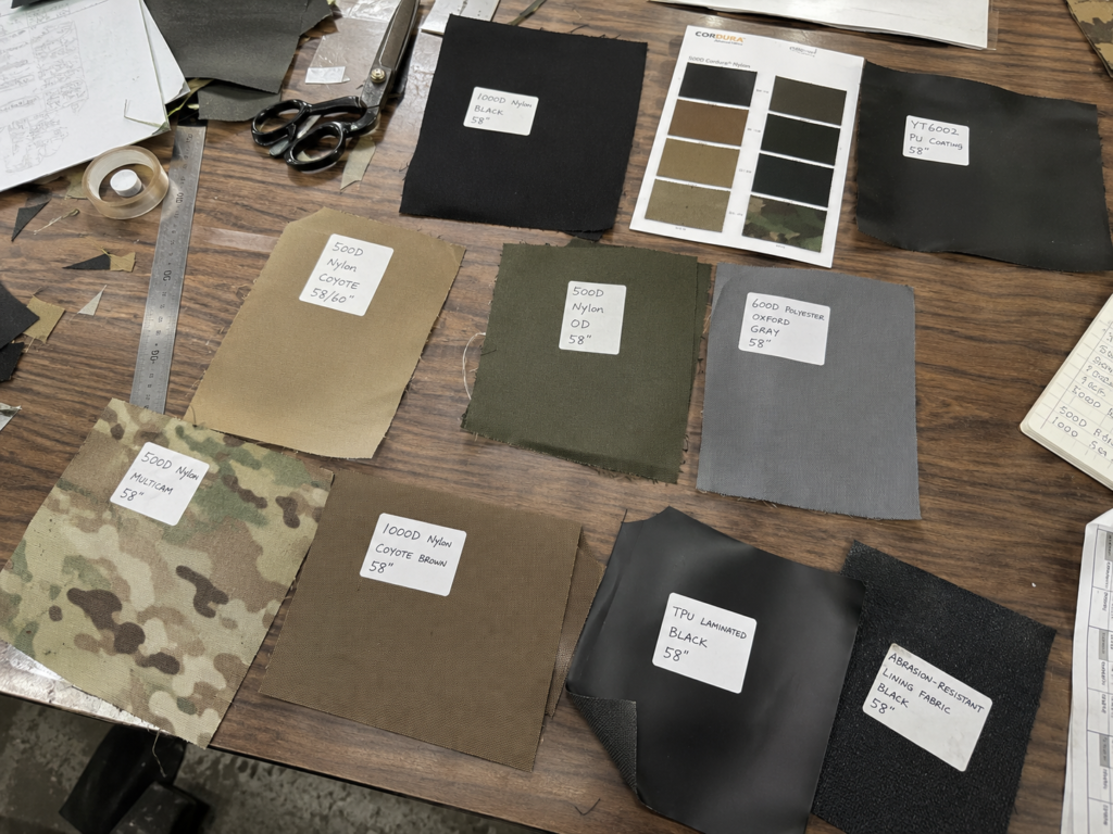 Labeled tactical fabric swatches and material samples arranged on a worktable