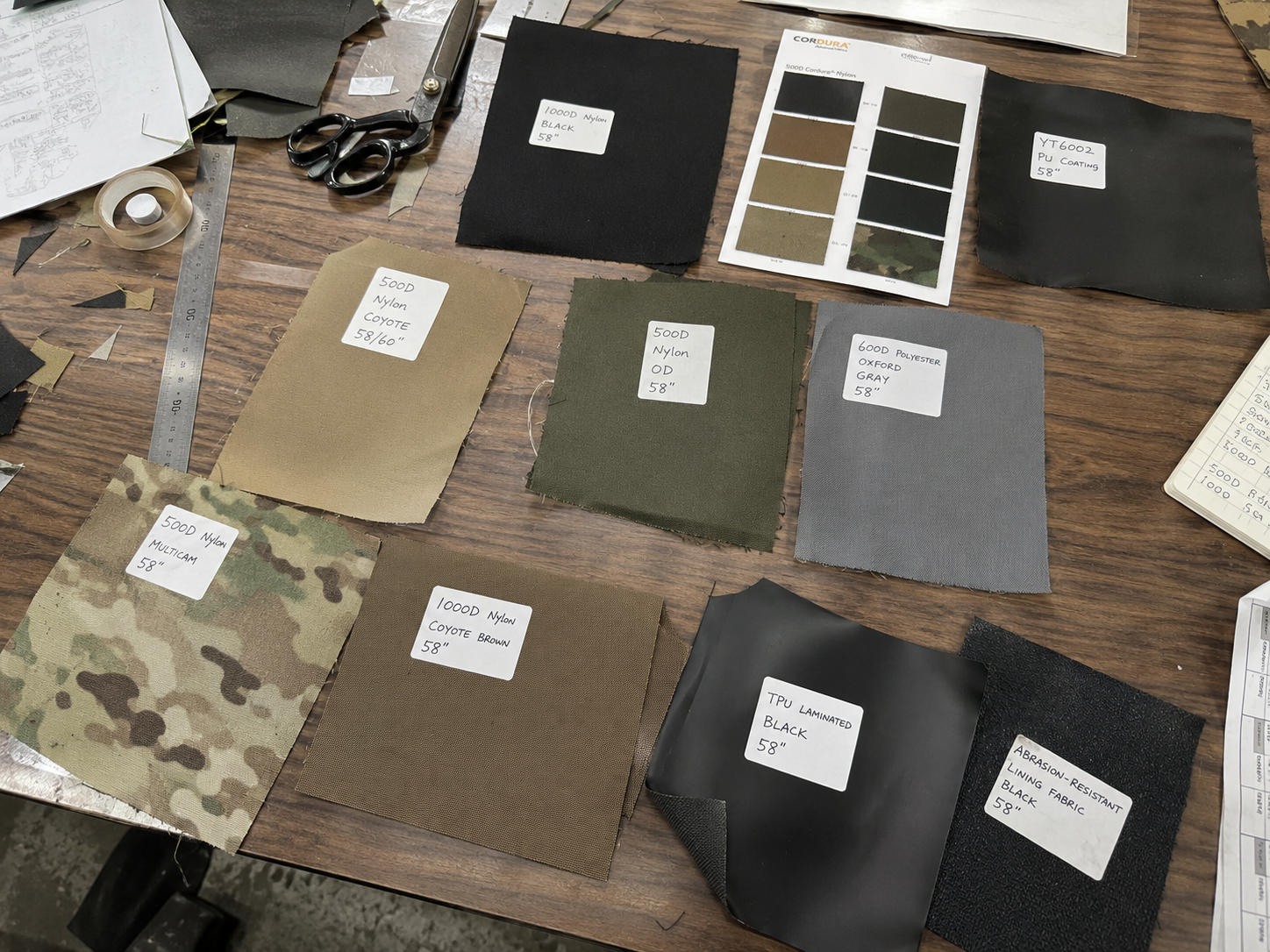 Labeled tactical fabric swatches and material samples arranged on a worktable