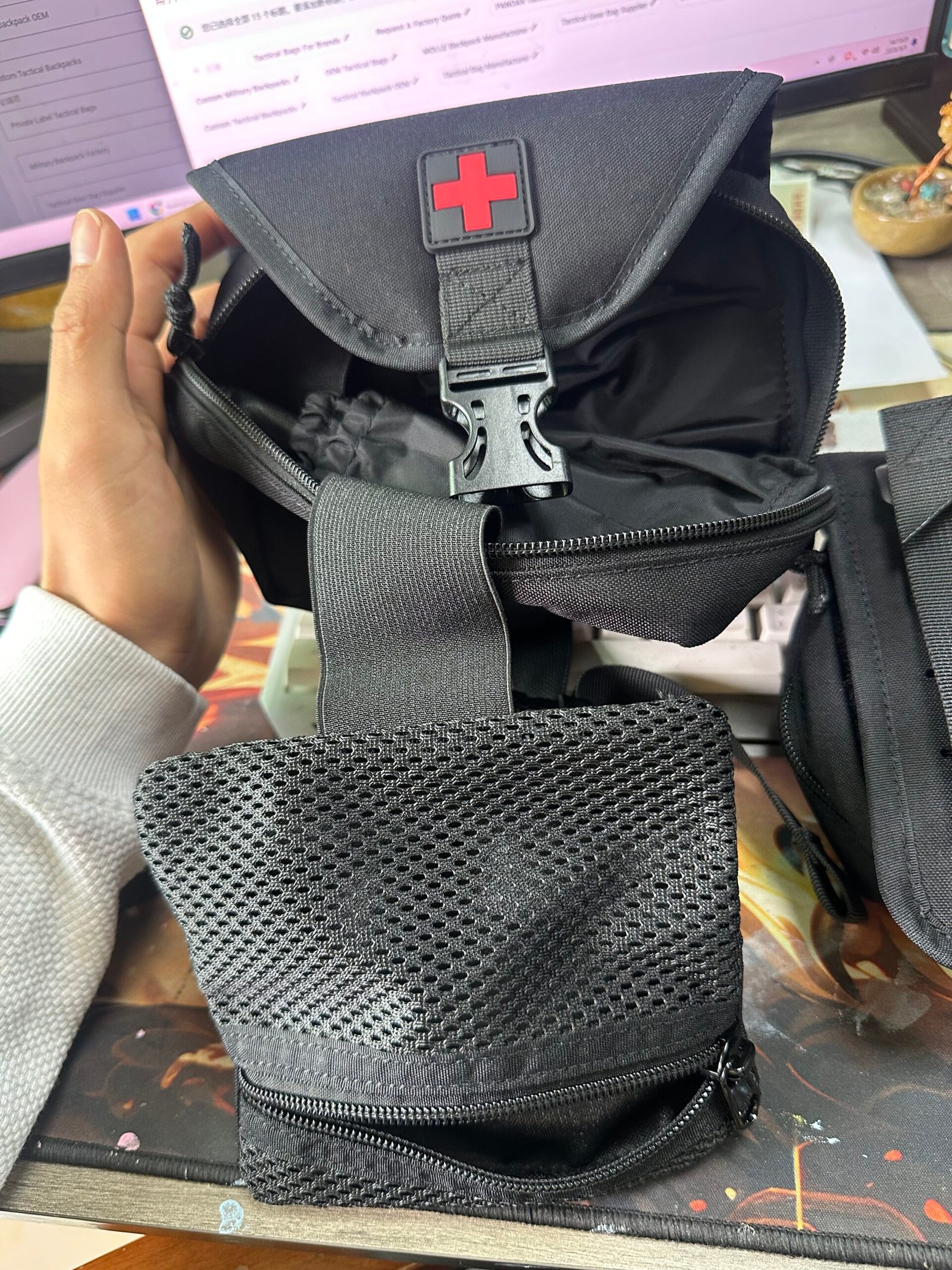 IFAK first aid pouch sample inspection showing mesh pocket, red medical cross marking and elastic retention strap