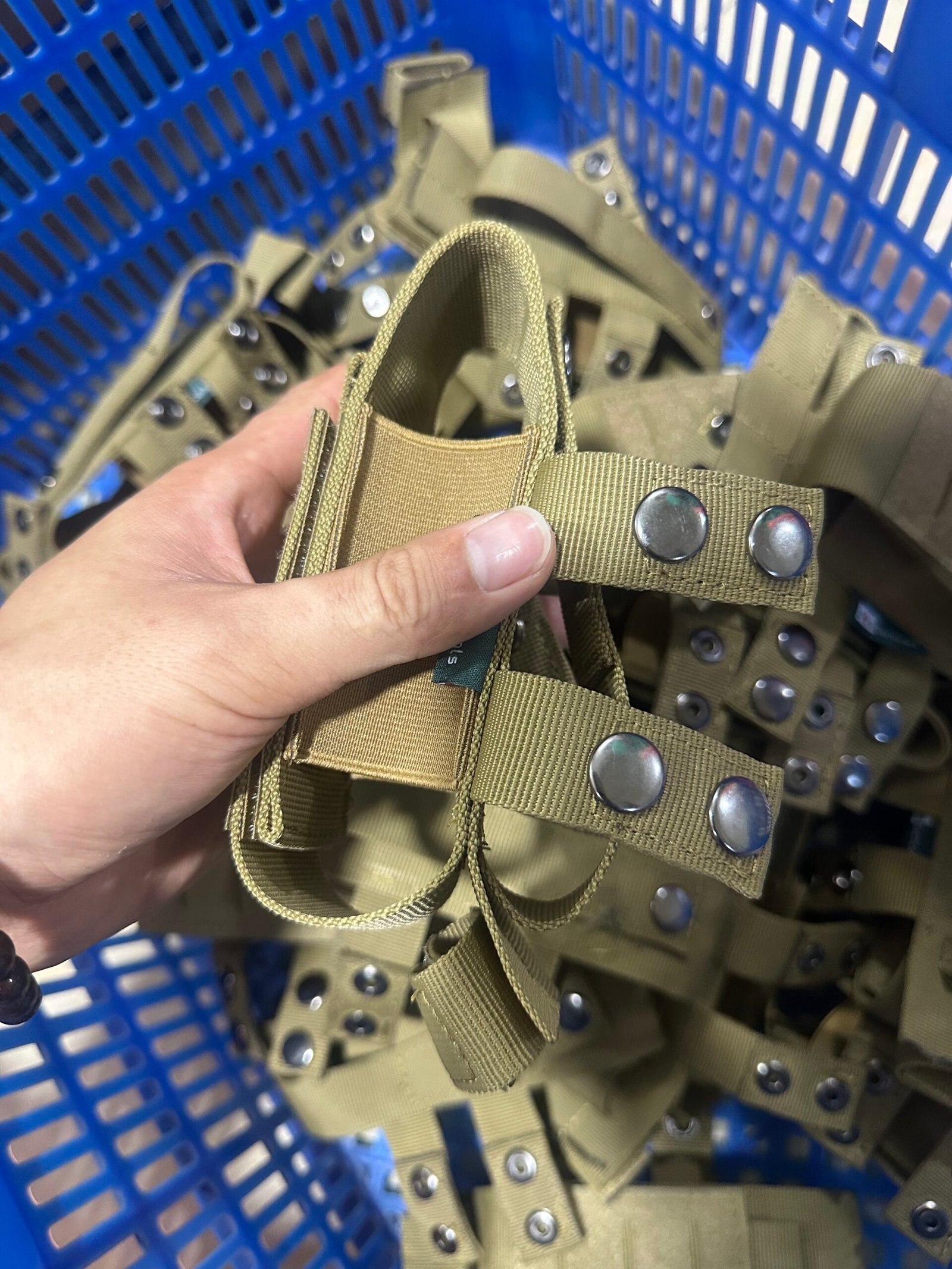 Coyote tan MOLLE webbing straps and snap fasteners prepared in bulk for tactical gear production