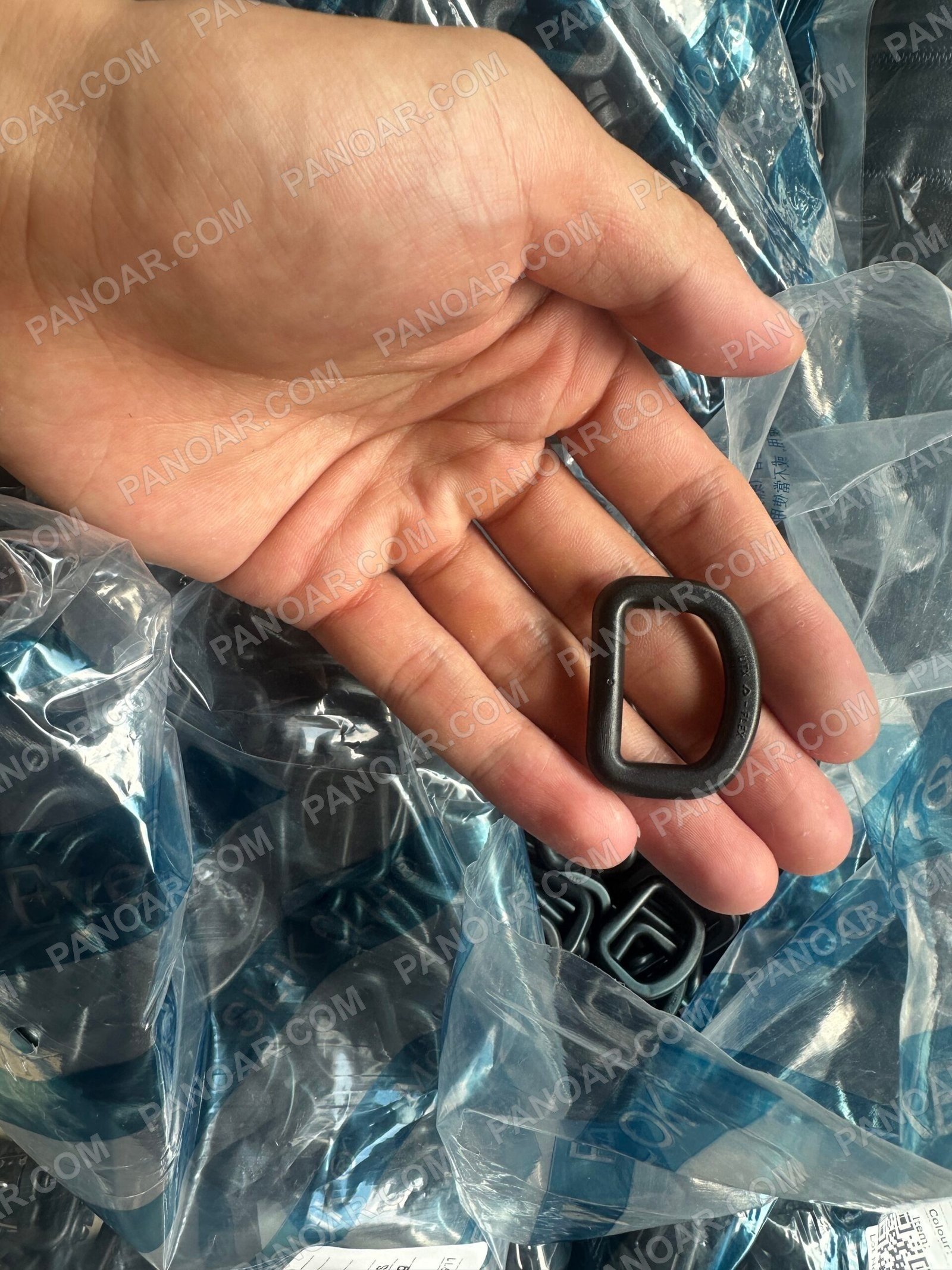 Hand holding a dark D-shaped ring