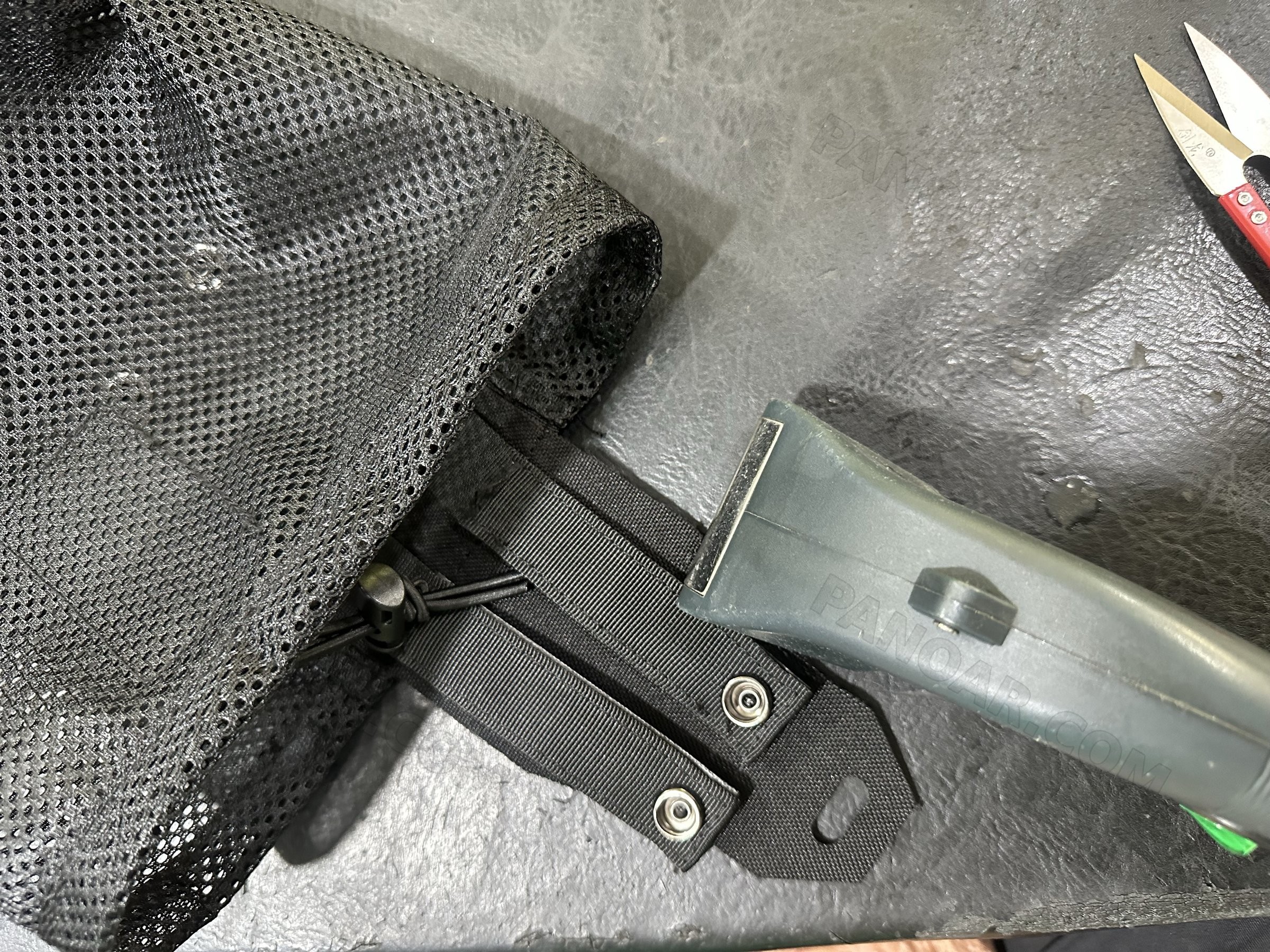 Black webbing strap with snap fasteners on a mesh bag
