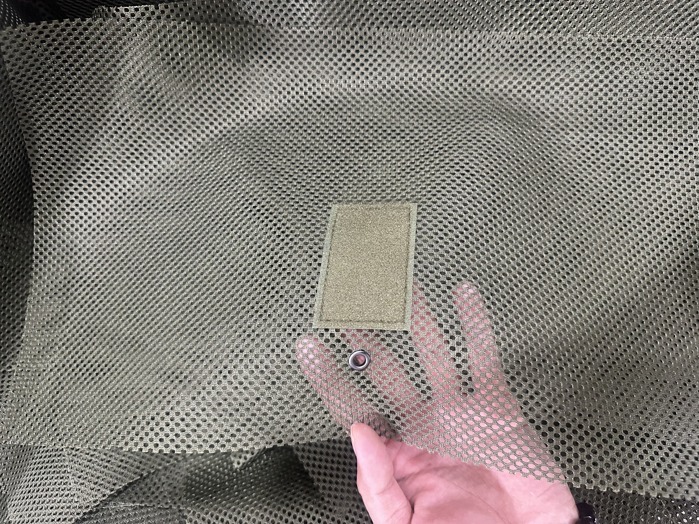 Rectangular hook-and-loop patch and metal eyelet on gray mesh fabric
