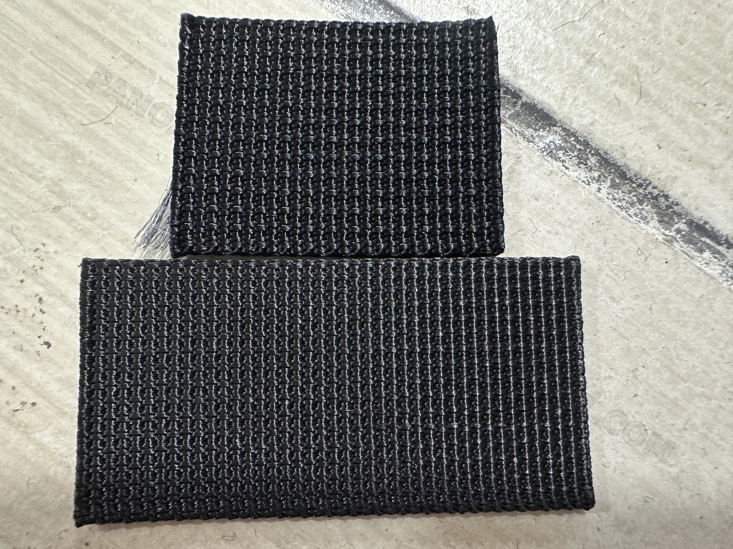 Two cut pieces of black textured fabric laid flat on a table