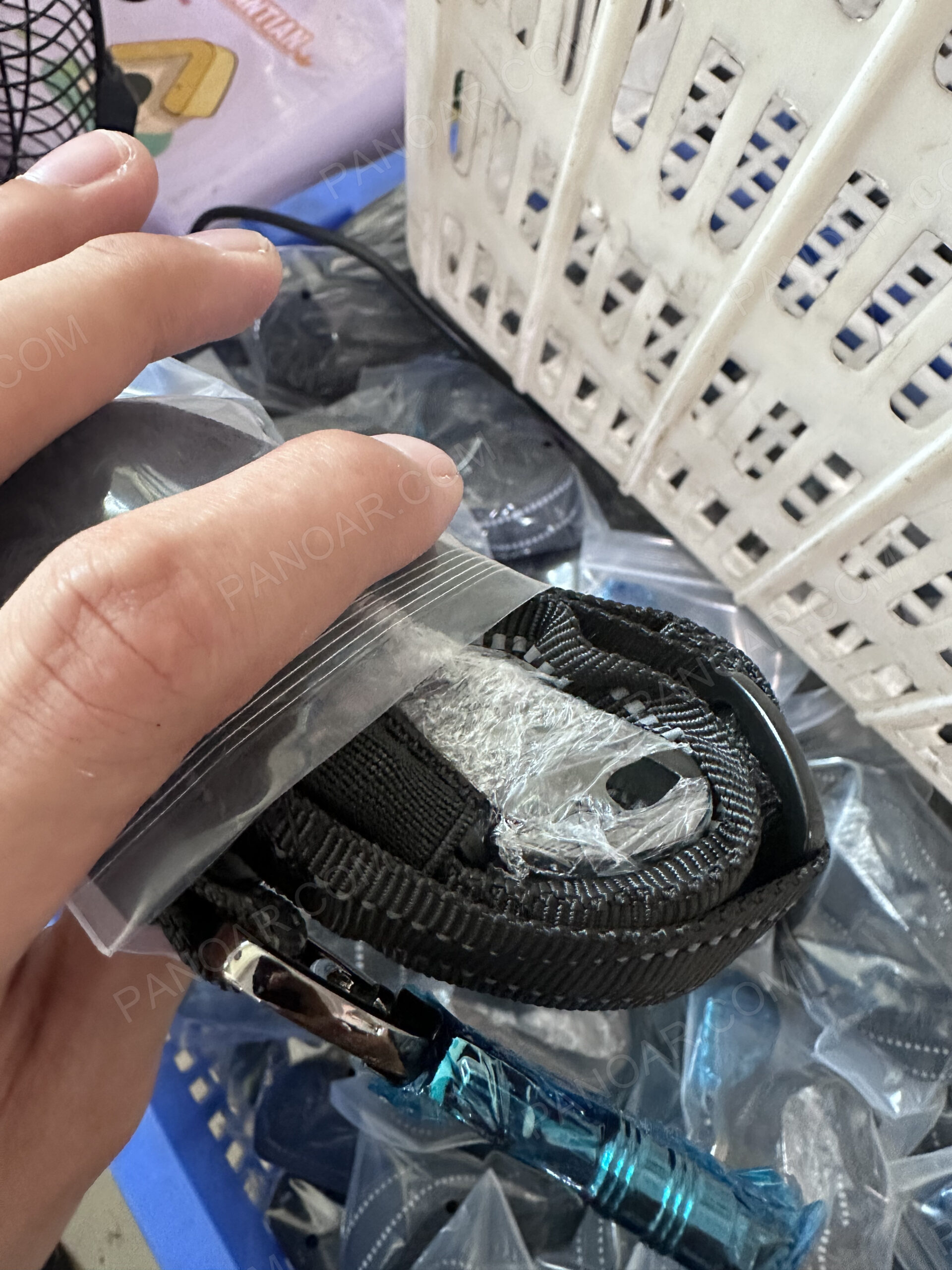 Wrapped hardware on a folded black dog collar beside an open polybag