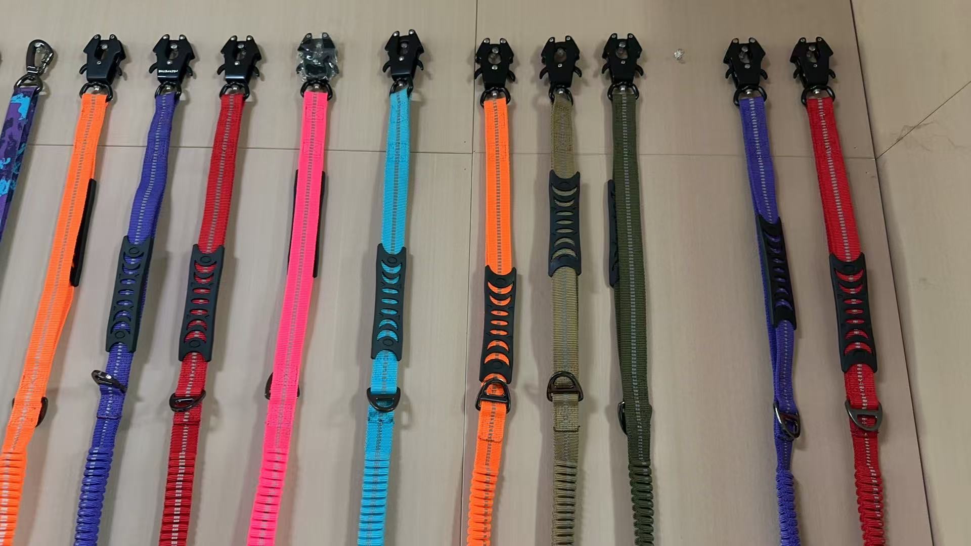 Colorful K9 leash samples laid out with black frog-style clips and different webbing colors.